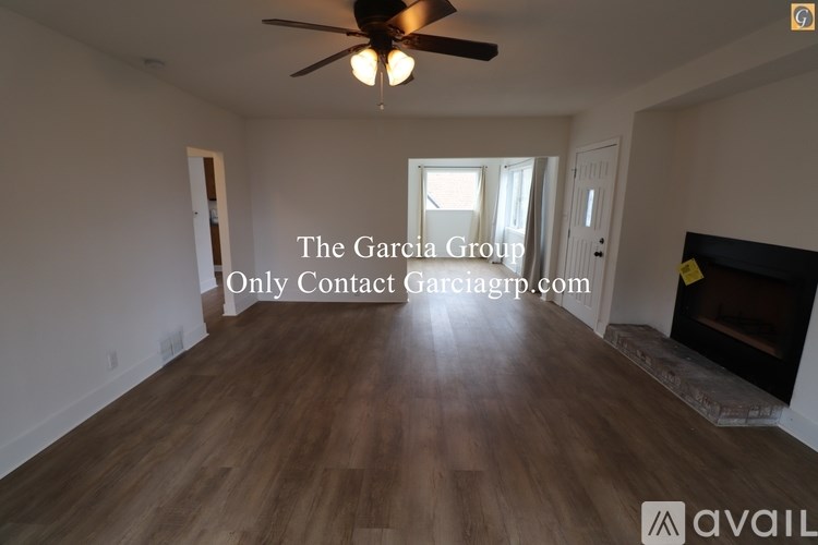 A room with a ceiling fan and a fireplace with a sign that says "The Garcia Group - Only Contact Garciagrp.com".