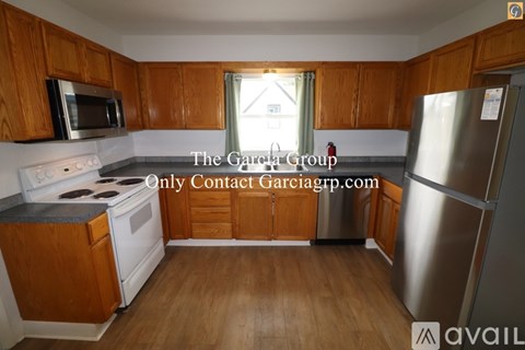A kitchen with wooden cabinets and a stainless steel refrigerator.