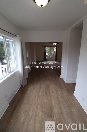 A room with wooden flooring and a window on the left side.