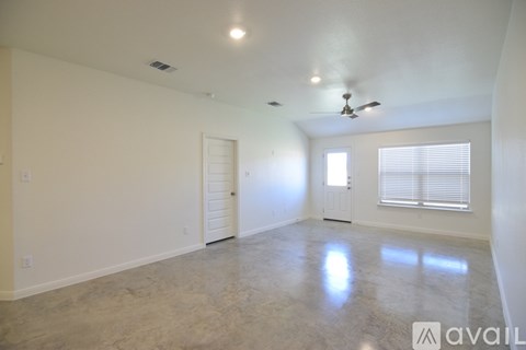 A spacious room with a ceiling fan and two windows.