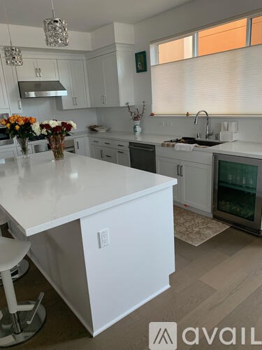 A kitchen with white cabinets and a white island.