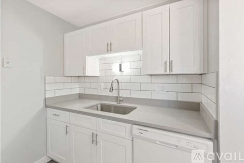 A kitchen with white cabinets and a stainless steel sink.