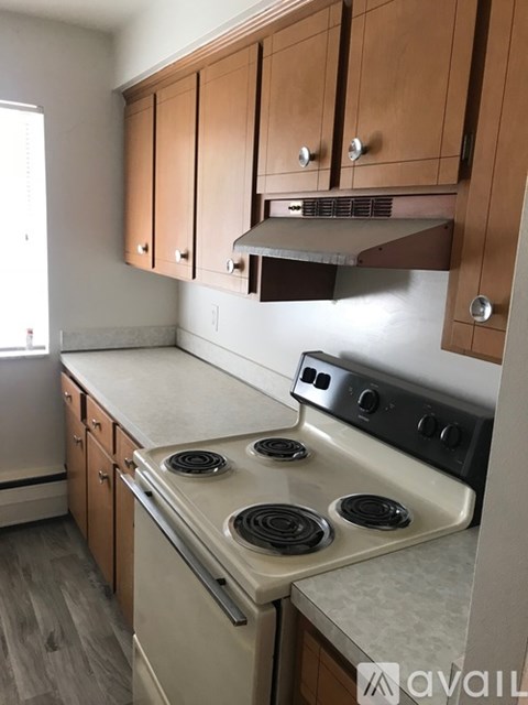 A kitchen with a stove top oven and wooden cabinets.
