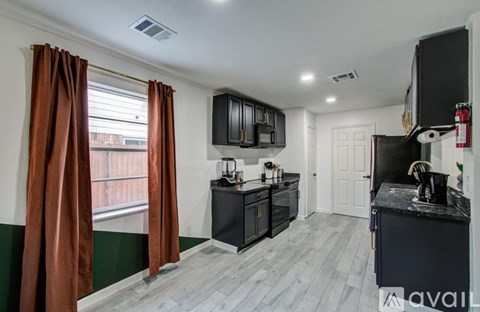 A kitchen with black cabinets and a black countertop with a white door in the background.