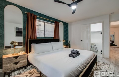 A bedroom with a large bed and a ceiling fan.