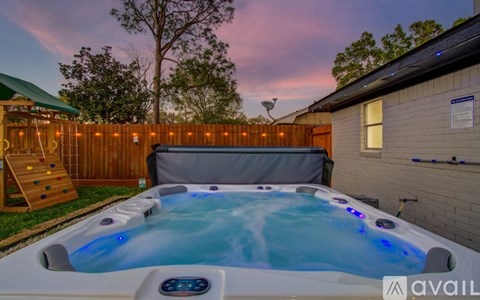 A hot tub is in the backyard with a wooden fence and a slide.