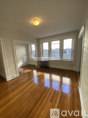 A room with wooden floors and a window overlooking a city.
