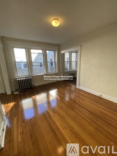A room with wooden floors and a window overlooking a cityscape.