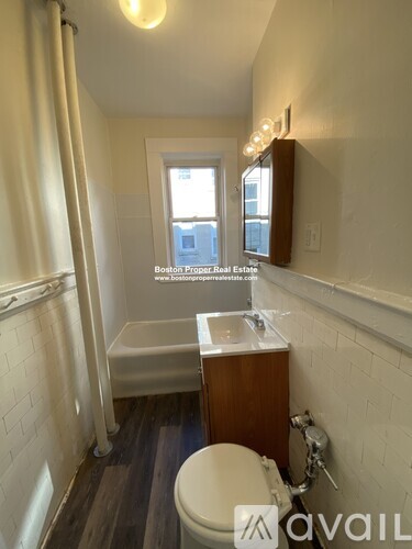 A bathroom with a toilet, sink, and window.