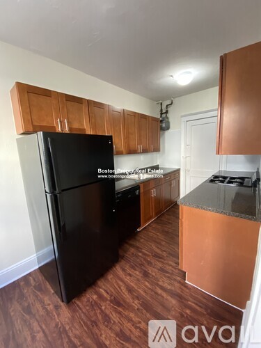 A kitchen with wooden cabinets and a black fridge.