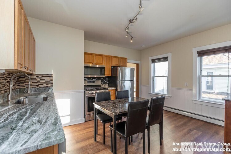 A kitchen with granite countertops and a dining table with chairs.