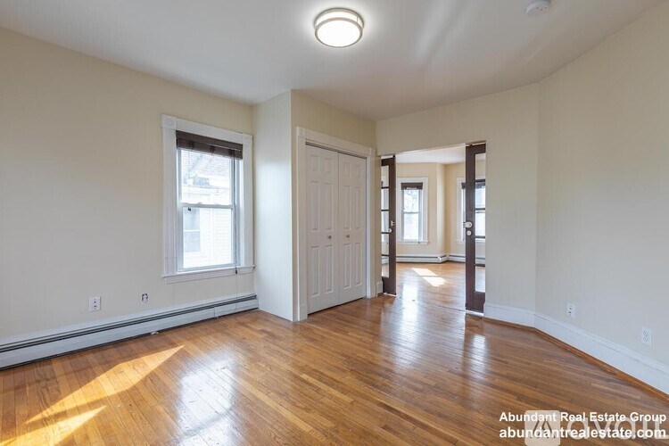 A spacious room with wooden floors and white walls.
