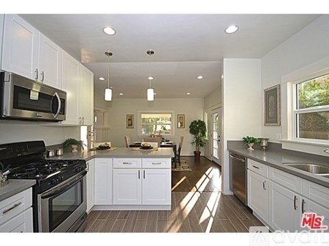A modern kitchen with white cabinets and stainless steel appliances.