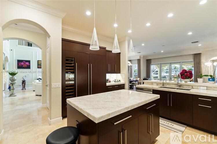 A modern kitchen with a central island and pendant lights.
