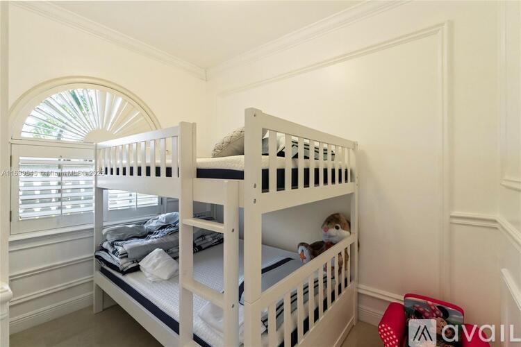 A white bunk bed in a room with a window.