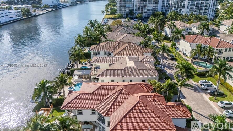 A row of houses with red roofs are situated by a body of water.