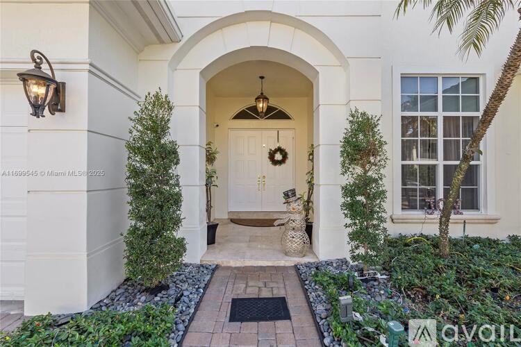 A white house with a black door mat and a wreath on the door.