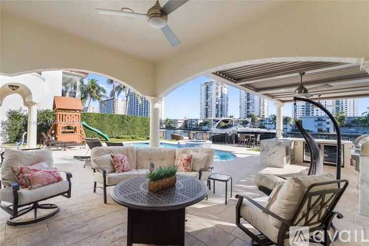 A patio with a table and chairs overlooking a pool and a city skyline.