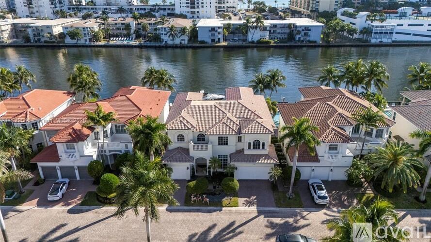 A row of houses with red roofs and white walls are surrounded by palm trees.