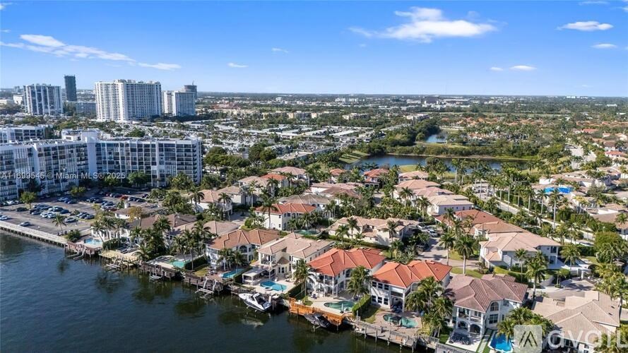 A bird's eye view of a residential area with houses and buildings near a body of water.