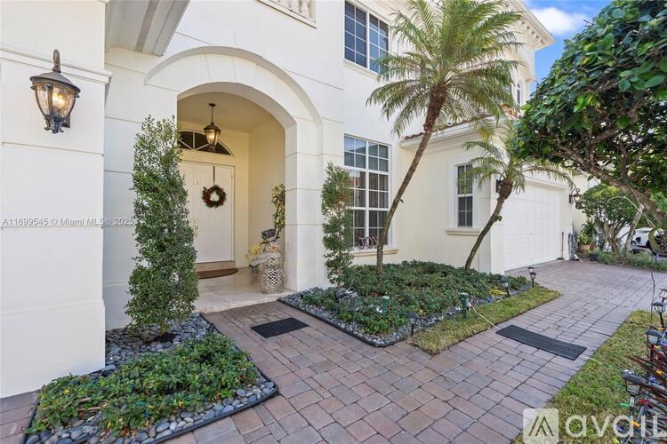 A white house with a wreath on the door and a palm tree in front.
