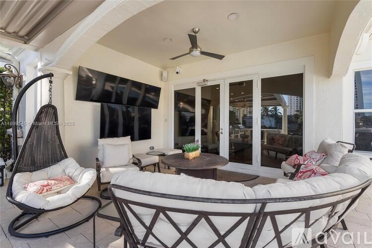 A patio with a white couch, a hanging chair, and a ceiling fan.