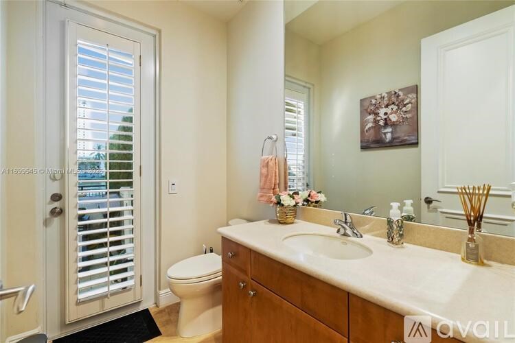 A bathroom with a toilet, sink, and a window with shutters.