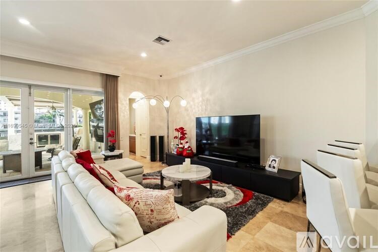 A living room with a white sofa, a black television, and a glass door leading to a balcony.