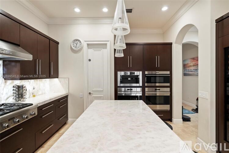 A kitchen with brown cabinets and a white marble island.