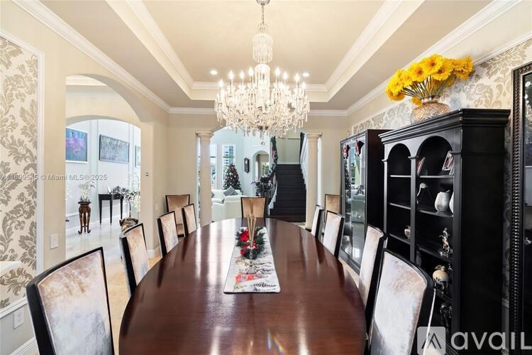 A long wooden table is surrounded by chairs in a room with a chandelier.