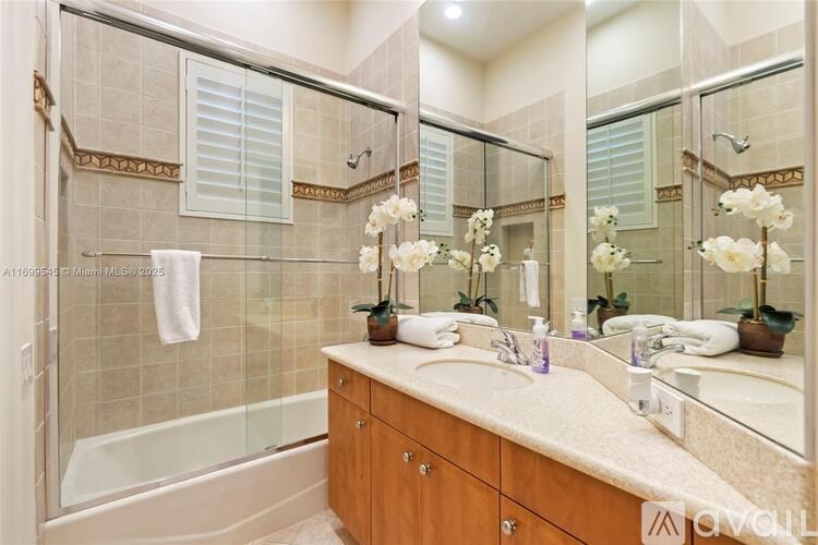 A bathroom with a large mirror, a white sink, and a glass shower enclosure.