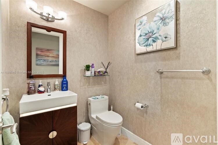 A bathroom with a toilet, sink, and a painting on the wall.