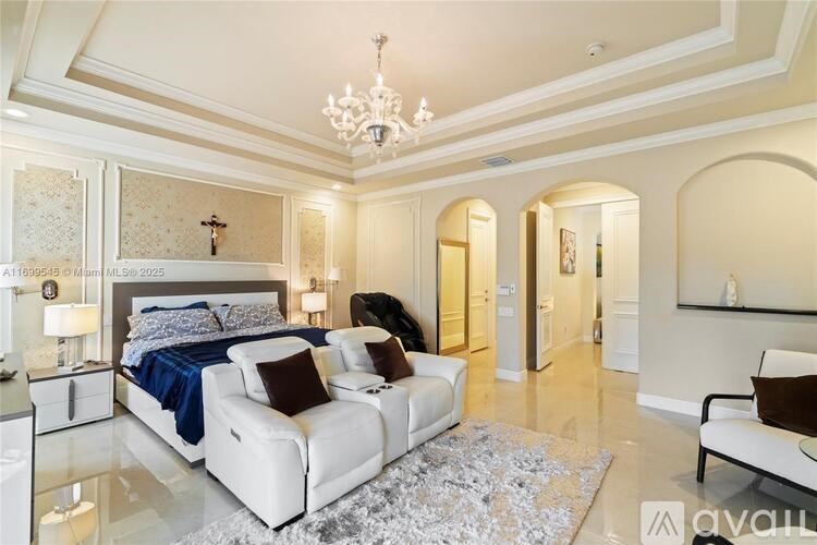 A bedroom with a large bed, a couch, and a chandelier.