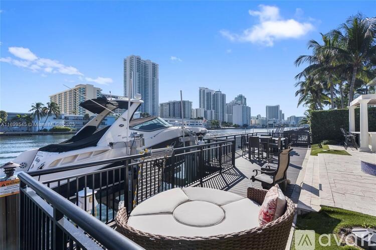 A luxurious outdoor setting with a table and chairs overlooking a marina with yachts and a city skyline.