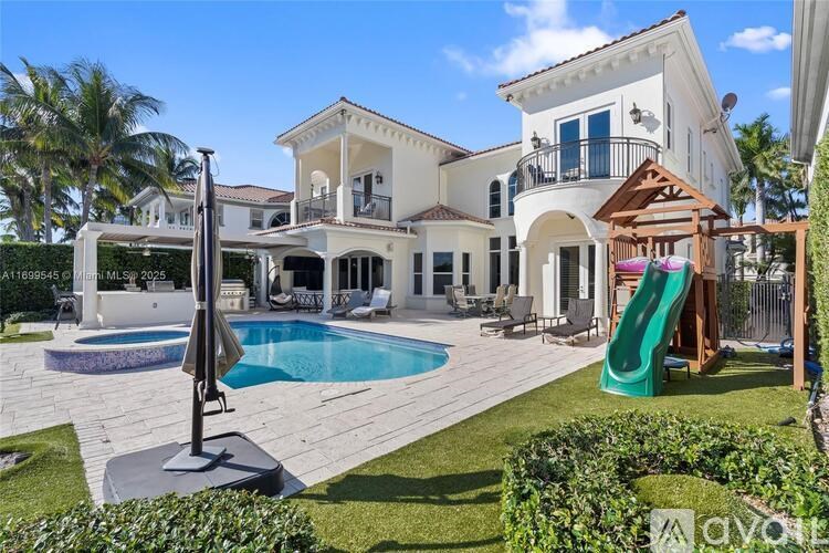 A large, white house with a pool and a green slide.