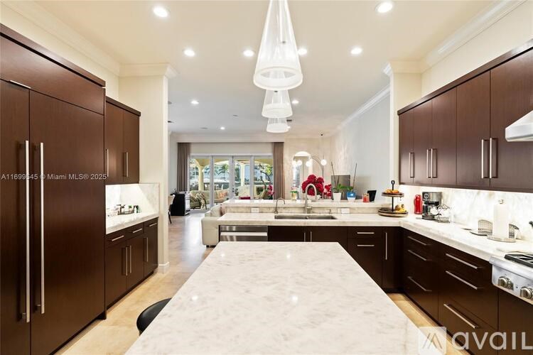 A modern kitchen with dark brown cabinets and a marble island.
