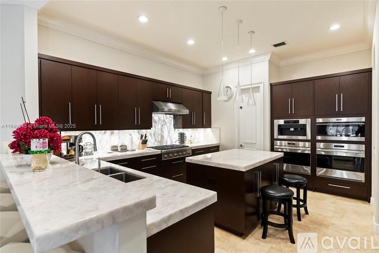 A kitchen with a marble countertop and dark brown cabinets.