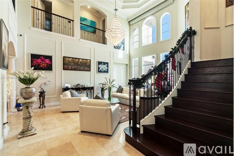 A large, well-lit living room with a staircase and a chandelier.