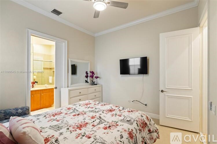 A bedroom with a floral bedspread and a flat screen TV mounted on the wall.