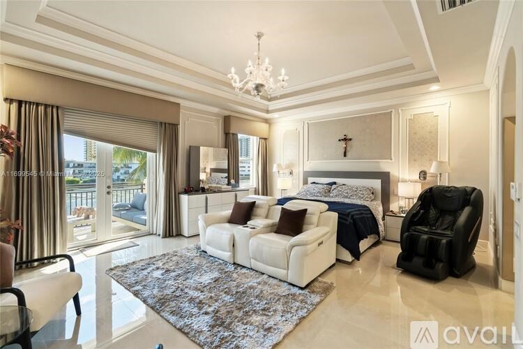 A large, well-furnished bedroom with a balcony overlooking the water.