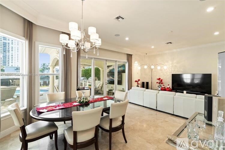 A dining room with a table set for six with red roses on the table.