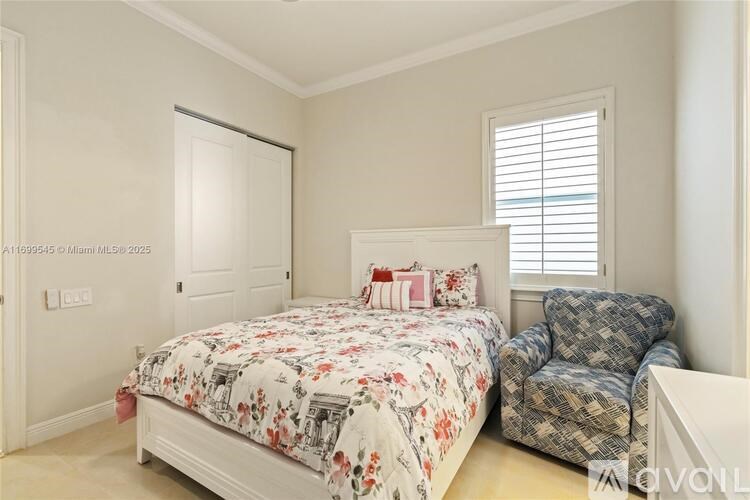 A bedroom with a bed and a chair.