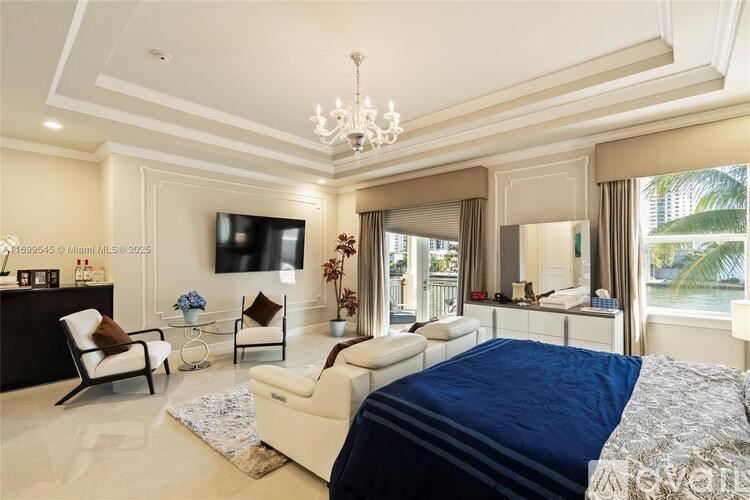 A bedroom with a large bed, a chair, a sofa, and a television.