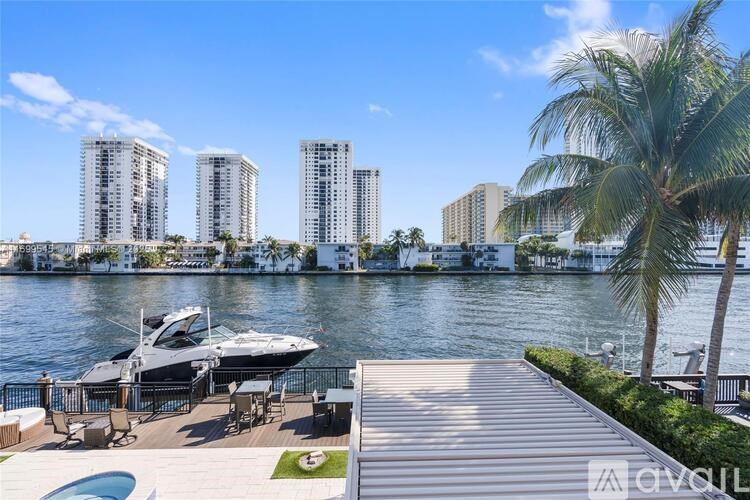 A luxurious waterfront property with a boat docked in the foreground and high-rise buildings in the background.