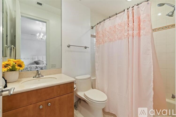 A bathroom with a pink shower curtain and a wooden vanity.