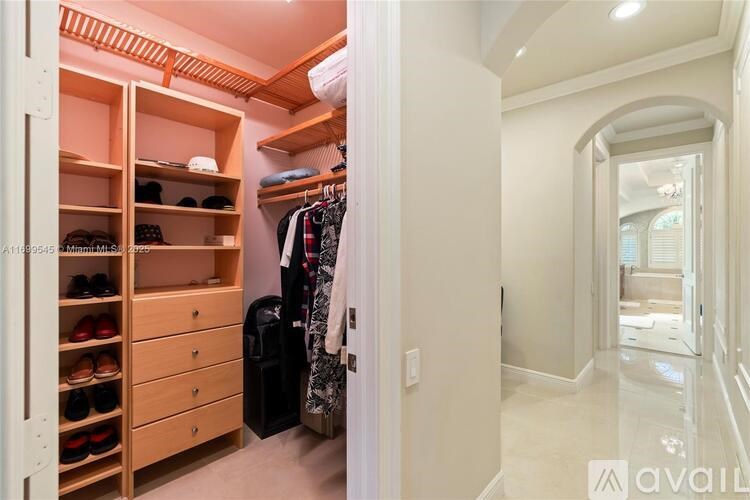 A spacious walk-in closet with wooden shelves and drawers.