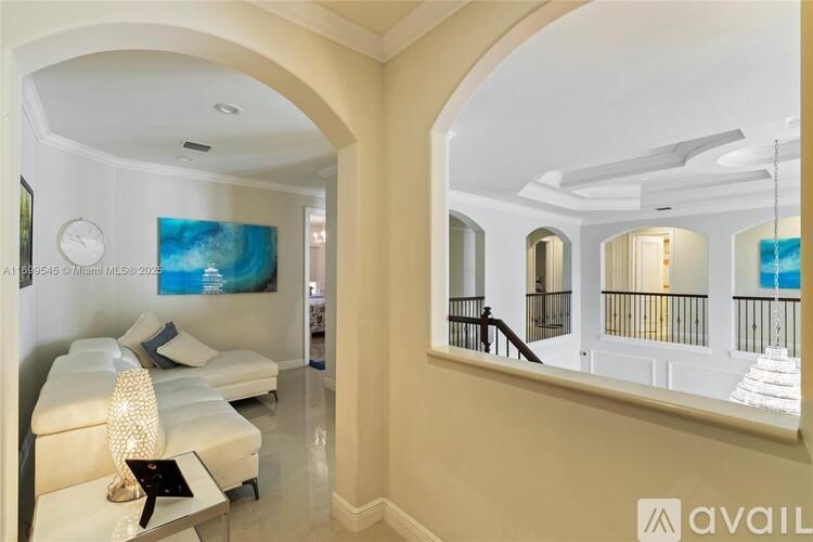 A living room with a white couch and a painting on the wall.