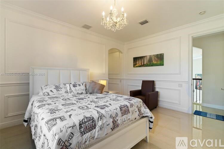 A bedroom with a large bed and a chandelier.