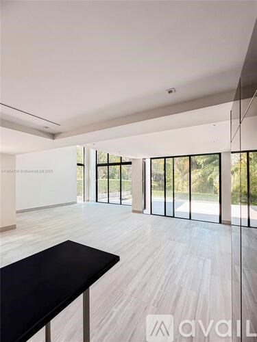 A spacious room with a black table and wooden flooring.