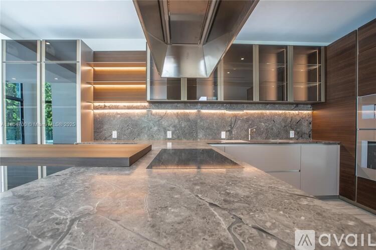 A modern kitchen with a marble countertop and stainless steel appliances.